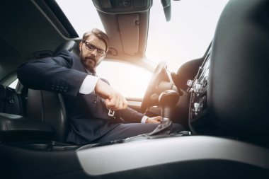 Sorumlu adam araba kullanmadan önce emniyet kemerini bağlıyor.