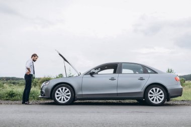 Stresli adam arıza arıyor. Araba kaputunun altında.