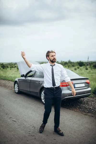 Bearded man trying to stop another driver to help with car
