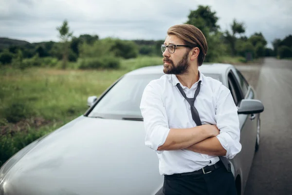 Портрет уверенного человека, стоящего рядом с машиной на дороге — стоковое фото