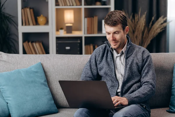 Bonito homem usando laptop durante o tempo livre em casa — Fotografia de Stock