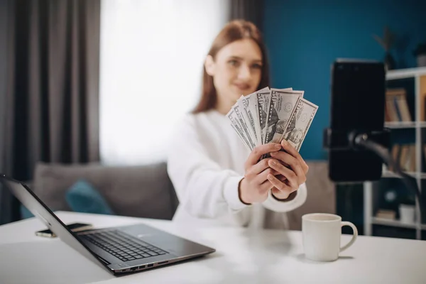 Kamerada dolar banknotlarını gösteren başarılı bir blog yazarı