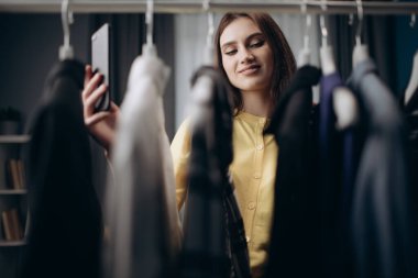 Kadın moda uzmanı elbise dolabında dikilip video çekiyor.