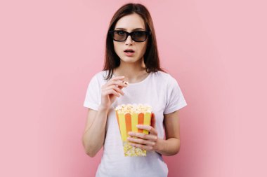 Üç boyutlu gözlüklü, patlamış mısırlı kız harika bir film izliyor.