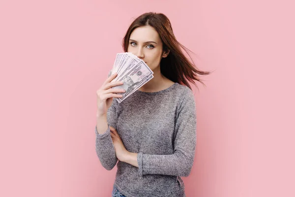 Hermosa chica de pie sobre fondo rosa con dinero en efectivo — Foto de Stock