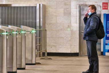 Rusya Haziran 2020. Moskova metrosu. Girişteki turnikelerin önünde bir adam duruyor ve telefonda konuşuyor. Rusya 'da koronavirüs salgını. viral enfeksiyon riski.