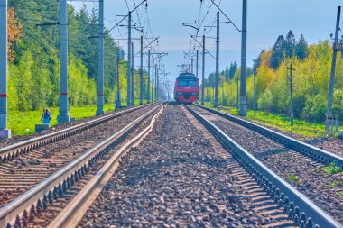 İnsanlar tren yolunda yürüyor, trene biniyor.