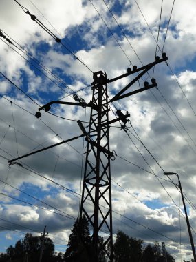 Demiryolunun üstündeki elektrik kablolarının metal desteği gökyüzünün arka planında