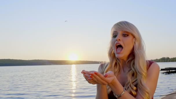 Portrait of attractive teen girl having fun with confetti on a background of lake. Slow motion. — Stock Video