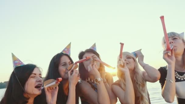 Zaprzyjaźnione grupy dziewcząt z okazji na plaży. Holiday rogi i kapelusze zaangażowanych. Zwolnionym tempie. — Wideo stockowe