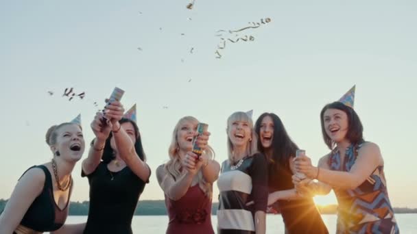 Eine Gruppe fröhlicher Freunde feiert die Mädchen am See. Feuerwerkskörper schießen nach oben. Zeitlupe. — Stockvideo