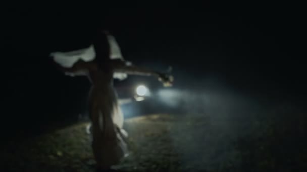 Noiva solitária assustadora em pé na estrada antes do carro à noite — Vídeo de Stock