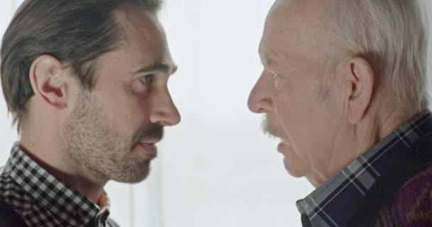Conflict sprake van een oude vader met een volwassen zoon in de buurt van het venster. Woede en ruzie in een volwassen familie - close-up. — Stockvideo