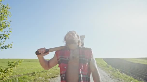 Travailleur du bûcheron marchant dans les terres agricoles par une journée d'été ensoleillée et chaude — Video