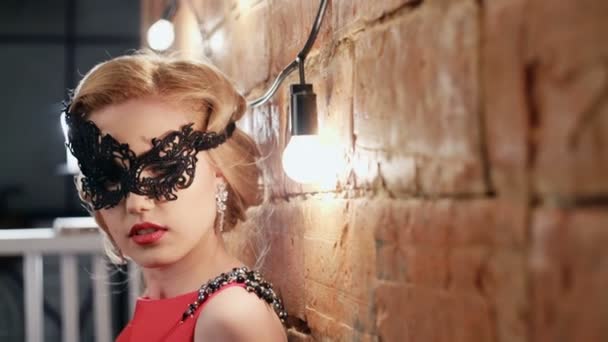Mooie blonde met carnaval masker in rode jurk. Opnamestudio in vintage sfeer. Ruwe videoverslag. — Stockvideo