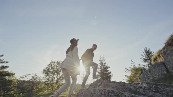 Elegáns nő és a férfi a hátizsák, Túrázás a sziklás hegyoldalban őt tartja a kezét, hogy segítse őt — Stock videók
