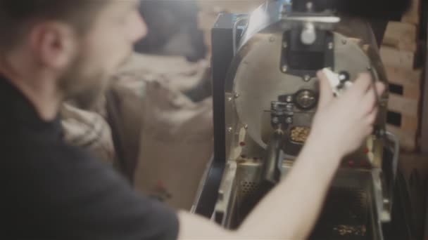 Hombre comprobando granos de café en máquina de tostado — Vídeo de stock