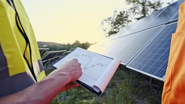 Güneş panelleri yakınındaki grafik kağıdına tutan adam — Stok video