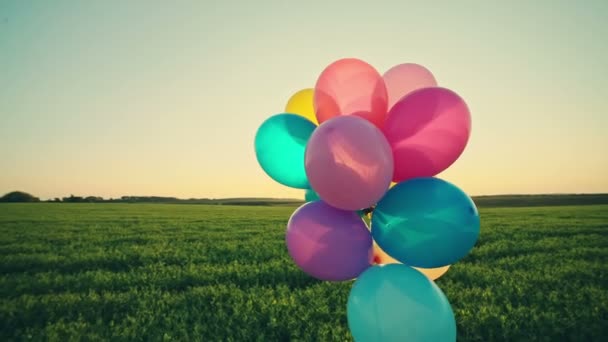 Маленькая девочка ребенок с воздушными шарами на открытом воздухе на фоне неба и поля. Видеозапись В. . — стоковое видео