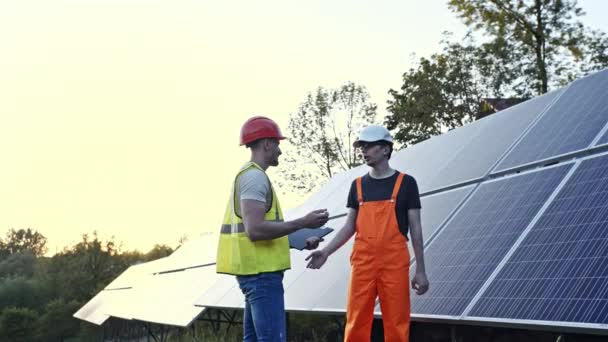 Двоє інженерів працюють над перевіркою та обслуговуванням обладнання на сонячній електростанції — стокове відео