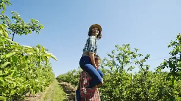 Ein paar Jungbauern amüsieren sich in einem Obstgarten — Stockvideo