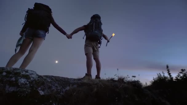 Jóvenes mochileros de pie sobre una roca cogidos de la mano — Vídeos de Stock