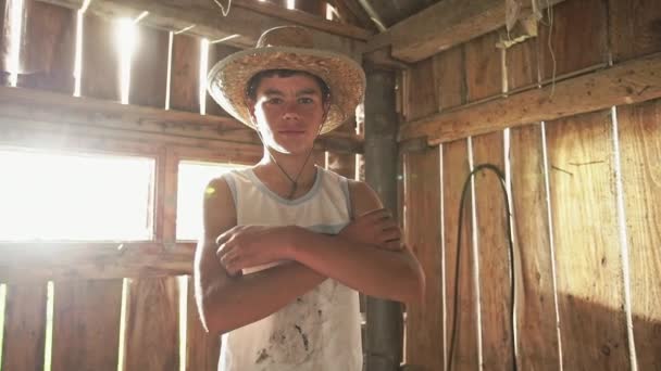 Teen ragazzo in cowboy cappello mantenere braccia incrociate e guardando fotocamera mentre in piedi in legno capannone — Video Stock