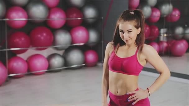 Uma menina de esportes com um belo corpo posa na sala de fitness — Vídeo de Stock