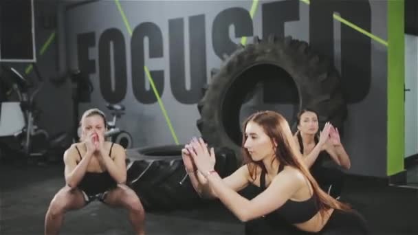 Stoere uithoudingsvermogen training voor jonge prachtige fitness modellen doen squats samen binnenshuis — Stockvideo