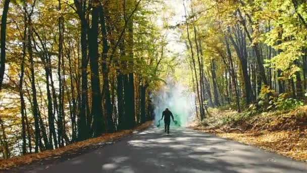 Человек бежит по осенней дороге, преследуя дым - замедленная съемка . — стоковое видео