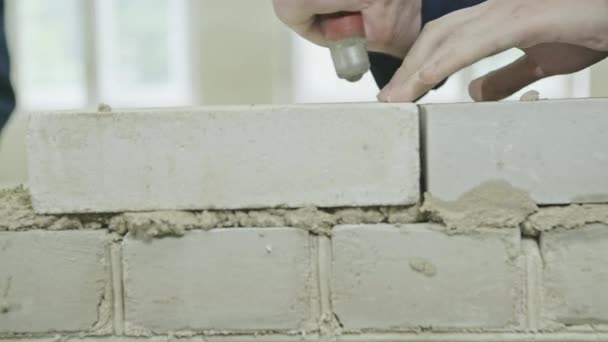 Travailleur pose de briques à l'aide de truelle sur le site de construction — Video
