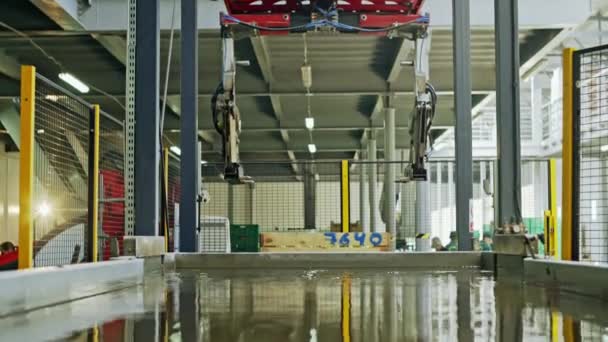 Grúa aérea interior que funciona en fábrica, vista desde un ángulo bajo y reflejada en la superficie del agua del depósito técnico — Vídeos de Stock