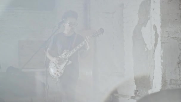 Man met de gitaar op het podium in rook. — Stockvideo
