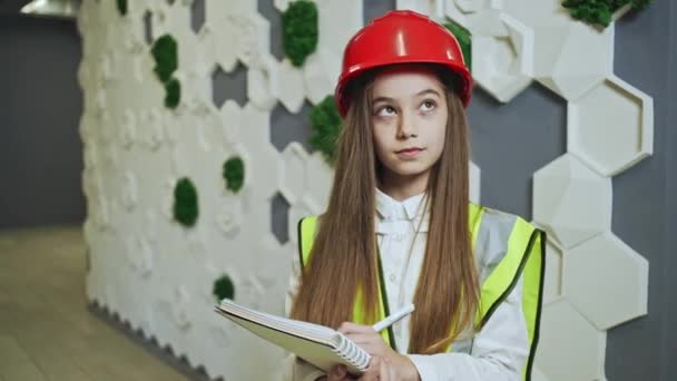 Petite fille en hardhat prendre des notes dans le bloc-notes — Video