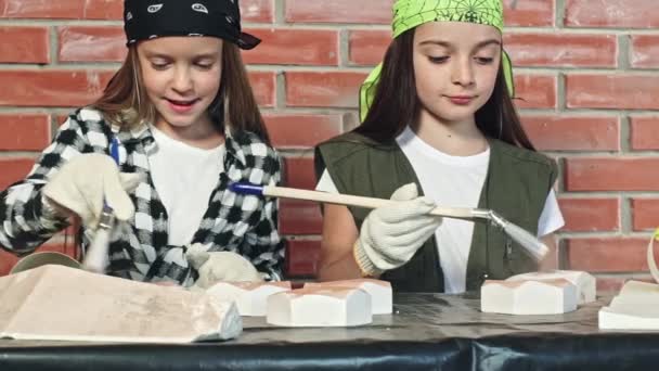 Двоє дітей малюють плитку білою перед стіною — стокове відео