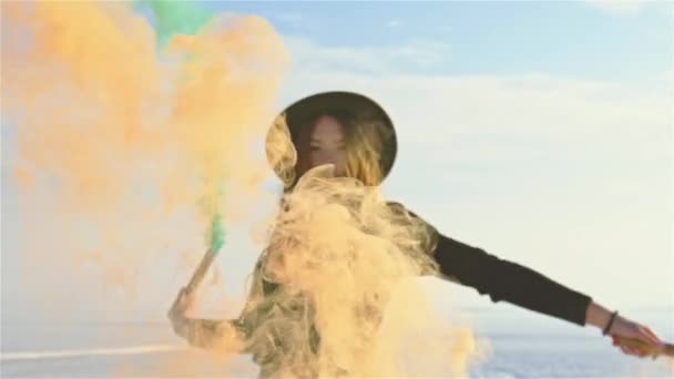 Chica joven con bomba de humo de color verde y naranja en la mano en el día de invierno . — Vídeos de Stock