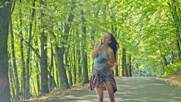 Ung snygg kvinna Rider skridskoåkning och lyssna på musik på en surfplatta — Stockvideo