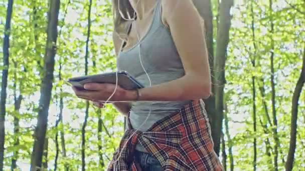 Menina sorridente em patins ao ar livre e ouvir a música em seu tablet — Vídeo de Stock