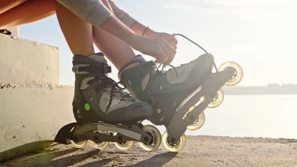 A mulher vai andar de patins. Sentado em um banco em um parque — Vídeo de Stock