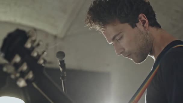 Joven guitarrista de rock sosteniendo una guitarra eléctrica con inspiración y pasión realiza una fuerte energía y música soul en los ensayos en el pub — Vídeo de stock