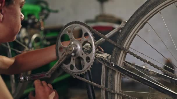 Jonge jongen is zeer geconcentreerde reparatie van een lekke band op zijn fiets alle door hemzelf - slwo beweging. — Stockvideo