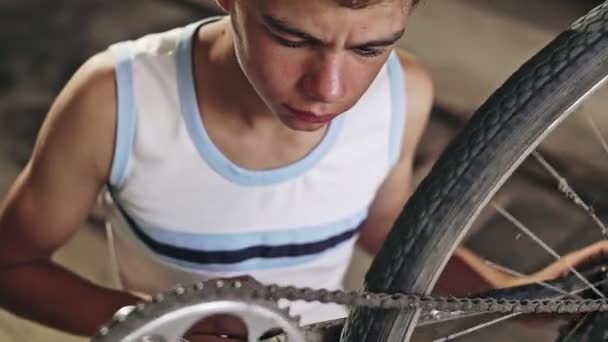 Ein kleiner Junge aus einer armen Familie überprüft im Sommer die Tauglichkeit seines Fahrrads in der Garage - Zeitlupe. — Stockvideo