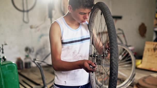 Tonårspojke reparera en cykel wheel i verkstad — Stockvideo