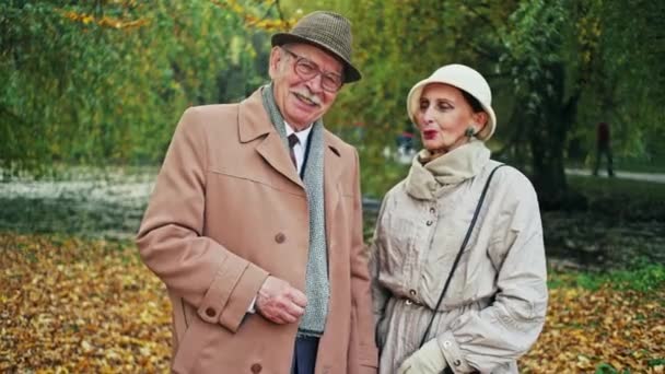 Een gelukkige ouderen paar chatten en lachen in een herfst Park - de liefde van de ouderen. — Stockvideo