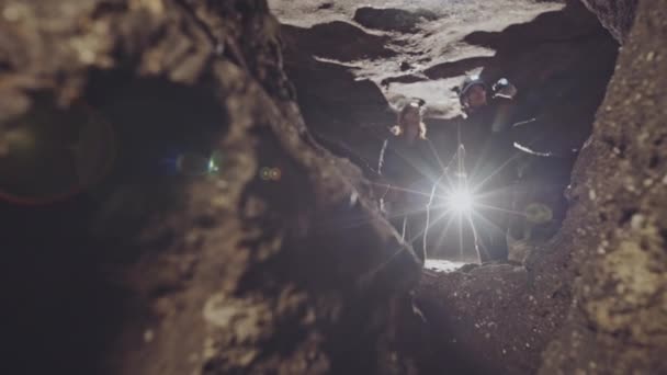 Homme et femme portant des casques avec marche dans une belle grotte explorant un chemin étroit ensemble — Video