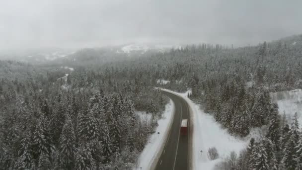 Camion roulant sur autoroute et montagnes enneigées brumeuses en arrière-plan - vue aérienne . — Video