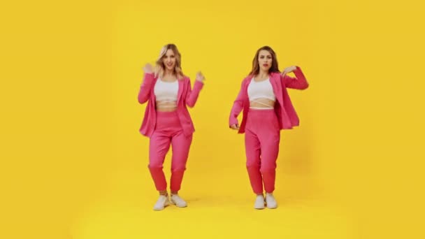 Dos chicas bailando sobre fondo amarillo — Vídeos de Stock