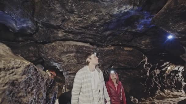 Grupp av turister vandrar i naturlig grotta tittar — Stockvideo