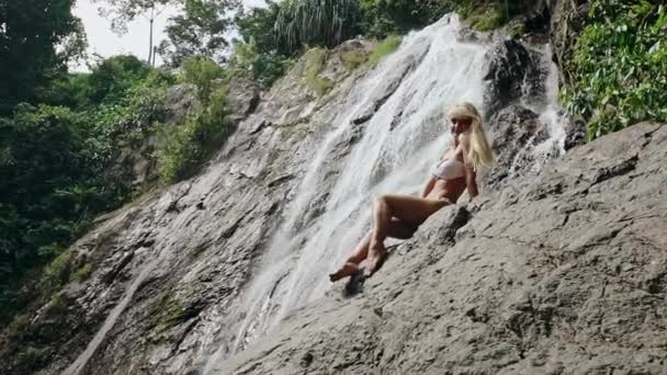 Schöne Frau im Bikini posiert in der Nähe von Wasserfall — Stockvideo