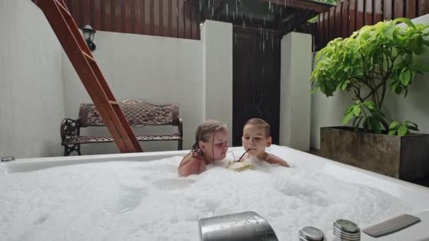 Barn med drink i tropiska jacuzzi — Stockvideo